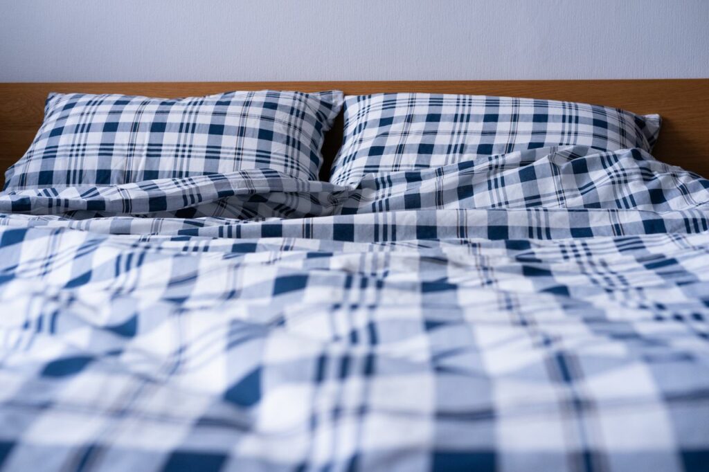 Comfortable double bed with blue plaid pattern bedding in a modern bedroom setting.